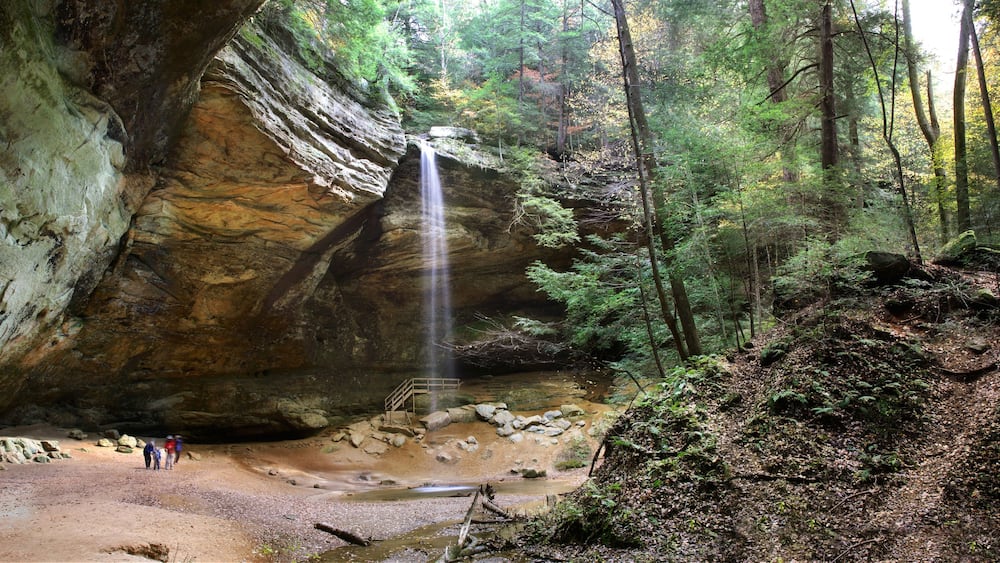 A waterfall cascading down a rocky cliff surrounded by a forest.