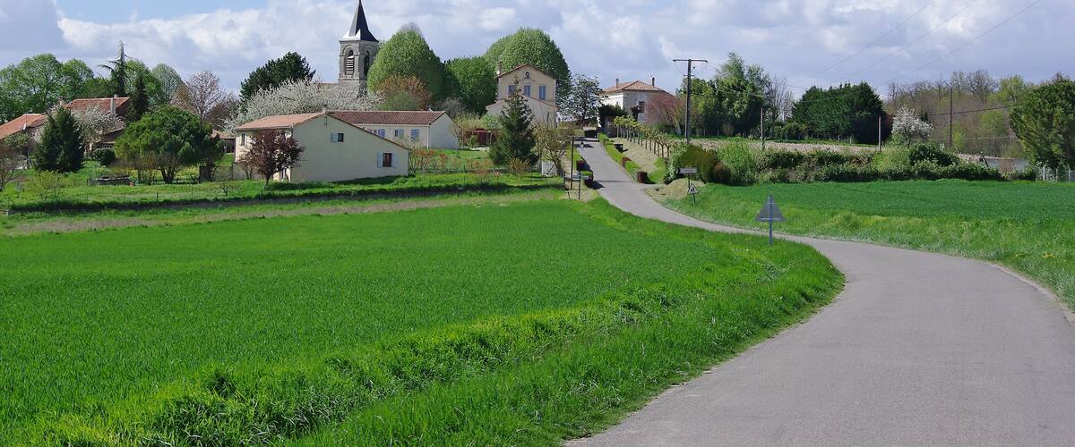 A rural village with a church, houses, and a green field.