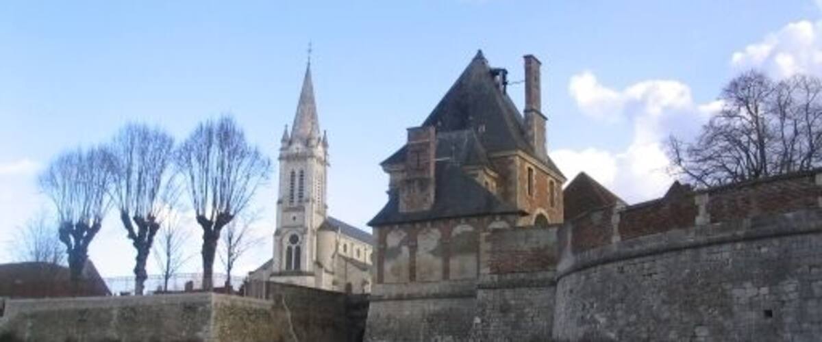 A historic building with a clock tower and a large, fortified structure.