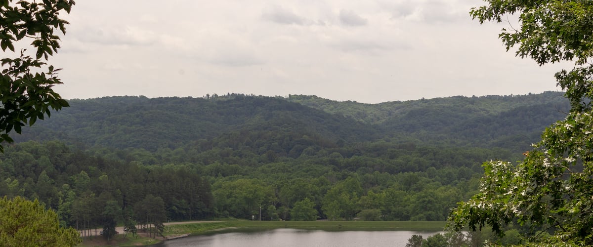 A lake surrounded by dense forest and rolling hills.