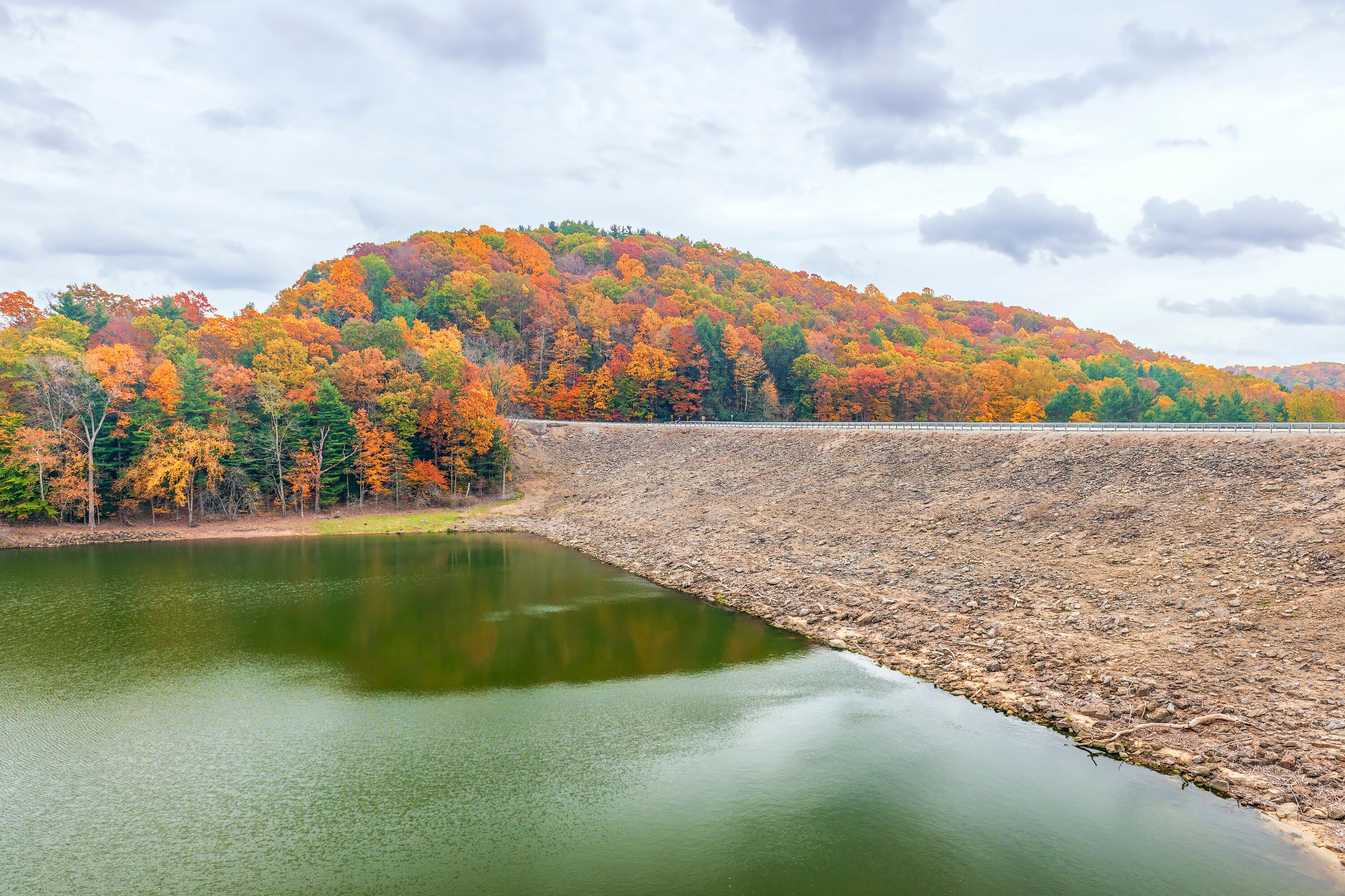 A lake with autumn-colored trees and a dam.