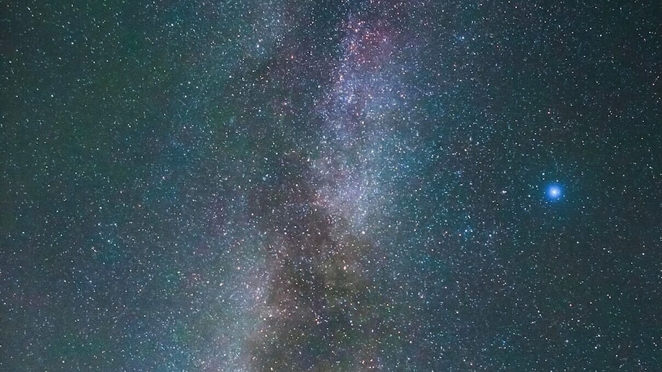 A rural road leading to a red covered bridge under a starry night sky with the Milky Way visible.