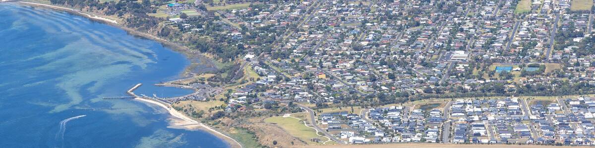 Aerial view of coastal city with beautiful beach and residential area near the ocean, Curlewis, Australia.