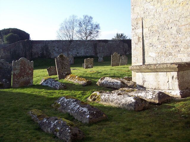 A cemetery with headstones and a stone wall.