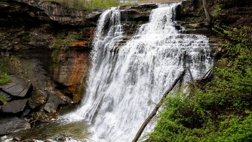 A waterfall cascading over rocky terrain surrounded by greenery.