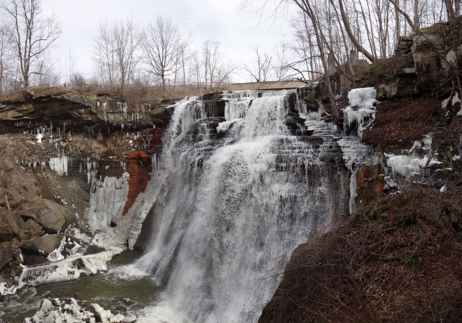A waterfall cascading over rocky terrain with icicles hanging from the edges.