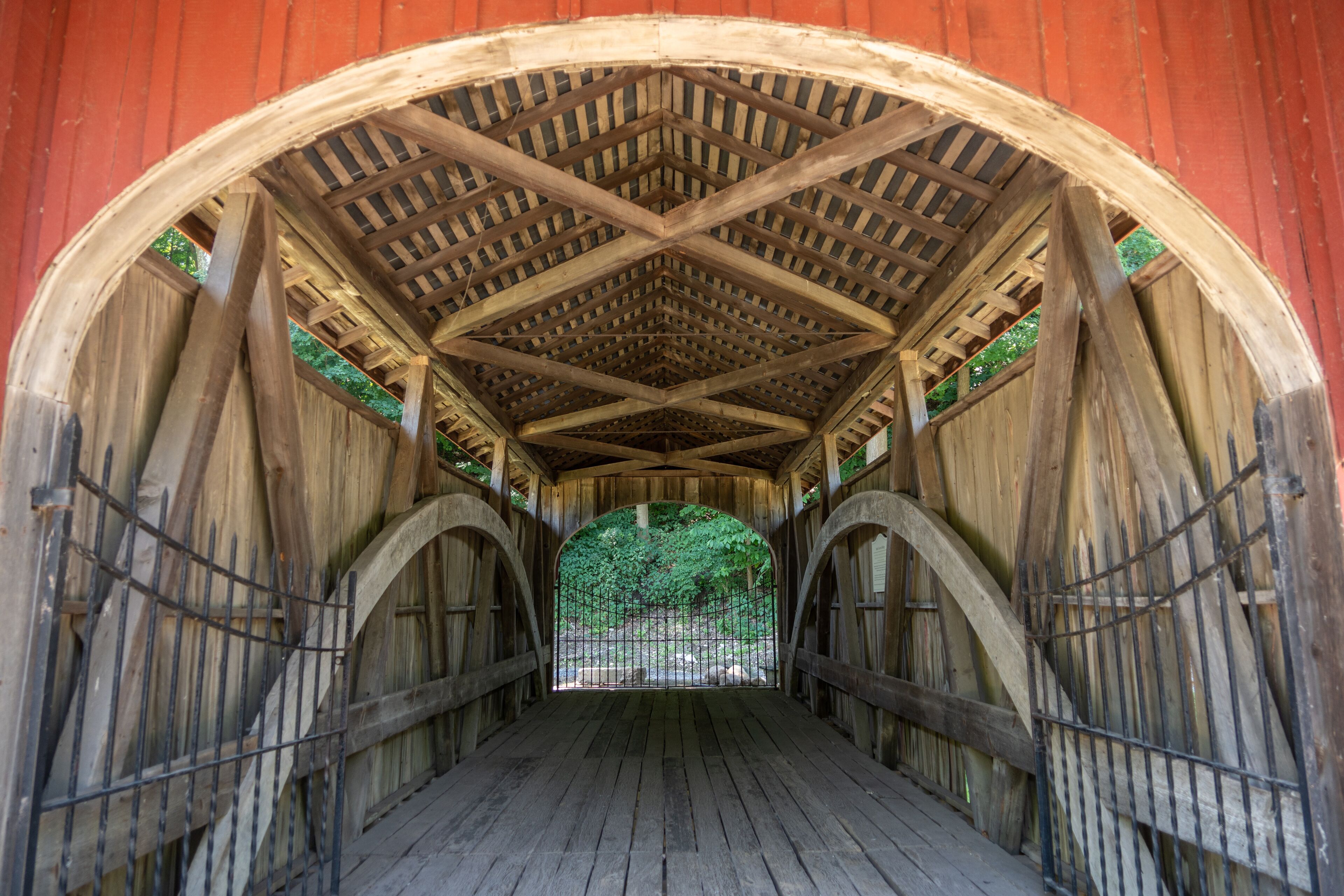 A covered wooden bridge with a wooden ceiling and arches.
