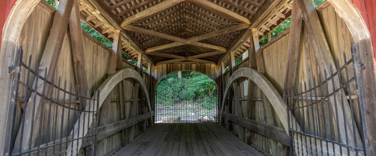 A covered wooden bridge with a wooden ceiling and arches.