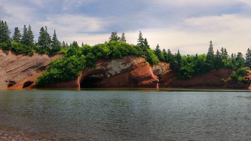 Panorama of children playing on pebble beach at sea caves of St Martins New Brunswick