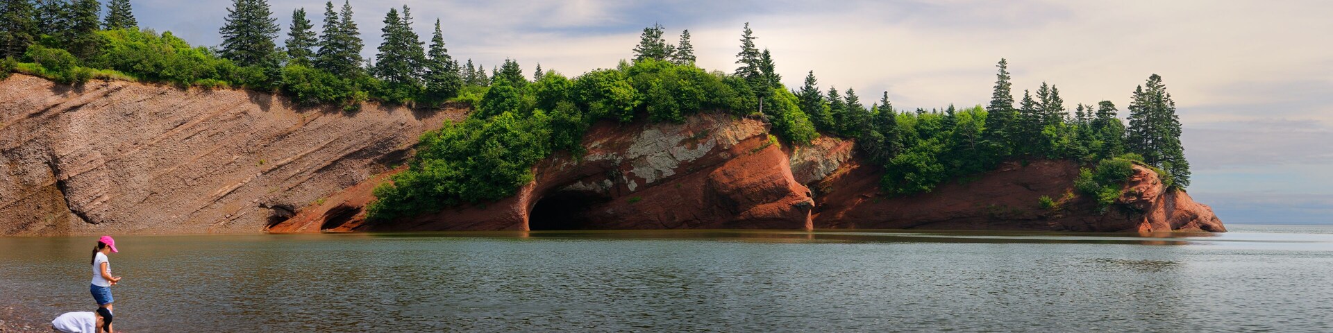 Panorama of children playing on pebble beach at sea caves of St Martins New Brunswick