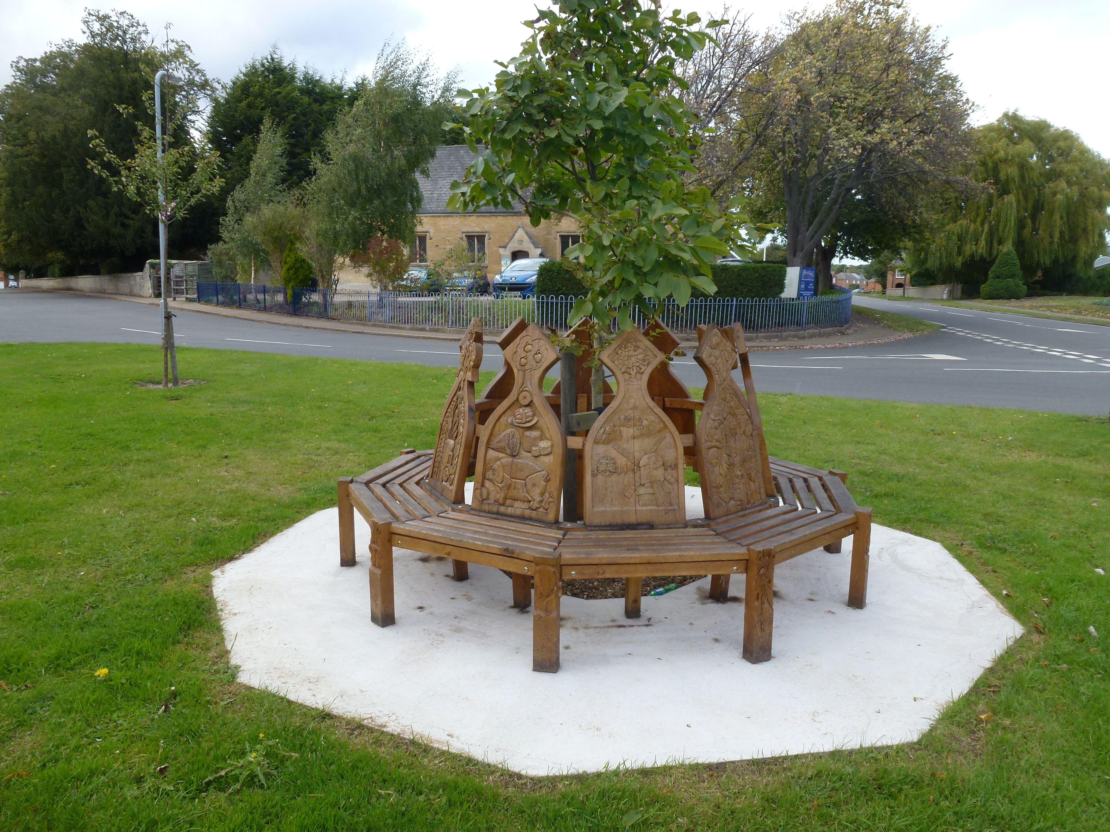 A wooden bench with intricate carvings in a park.