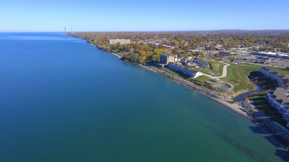 A coastal town with a marina, residential buildings, and a bridge in the distance.