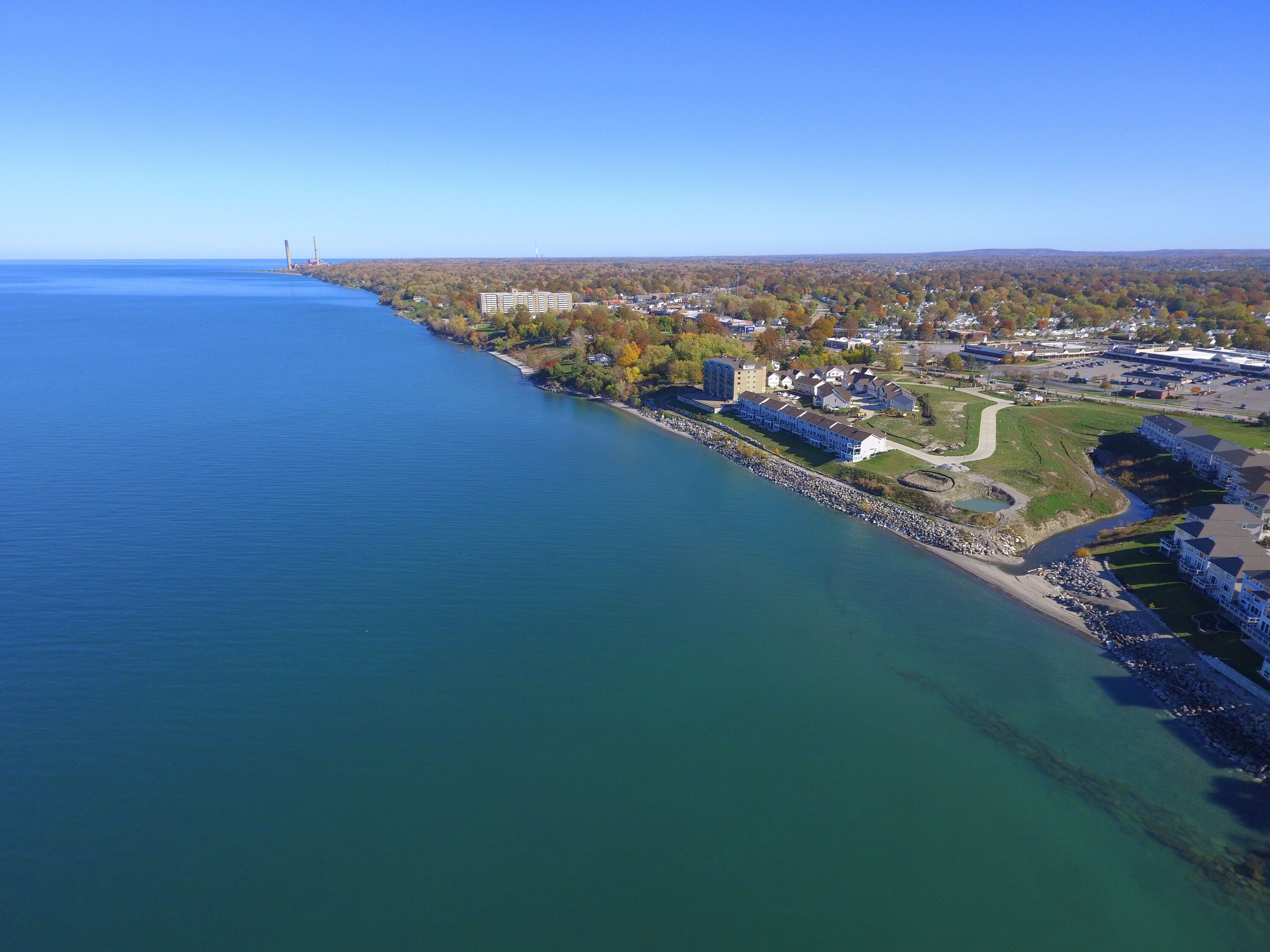 A coastal town with a marina, residential buildings, and a bridge in the distance.