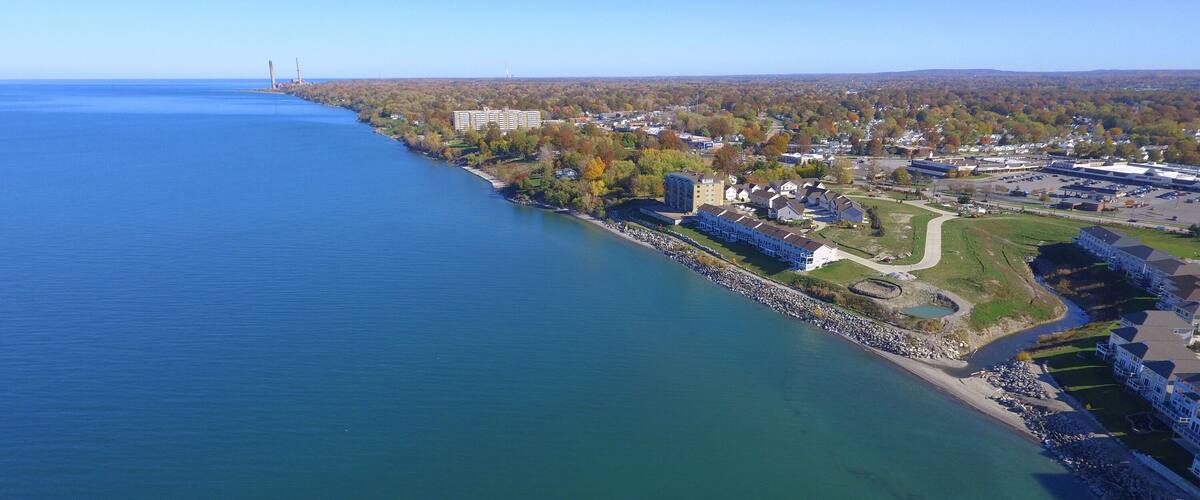 A coastal town with a marina, residential buildings, and a bridge in the distance.