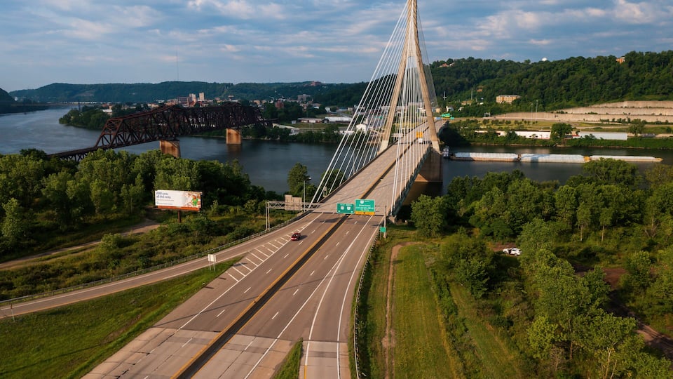 A suspension bridge over a river with a highway passing underneath.