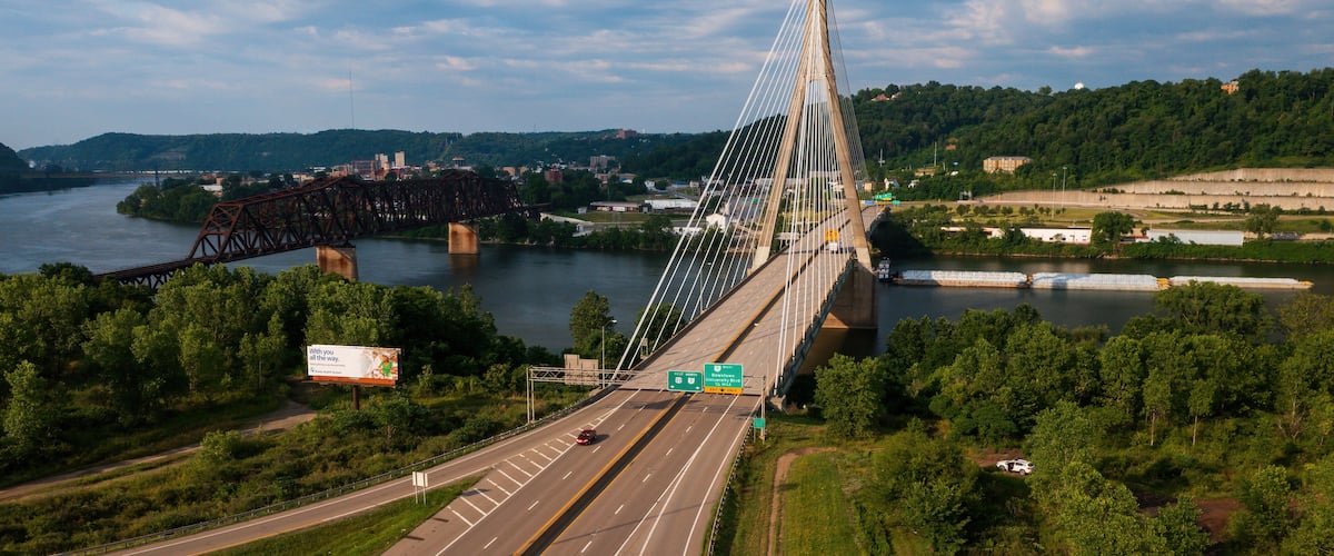 A suspension bridge over a river with a highway passing underneath.