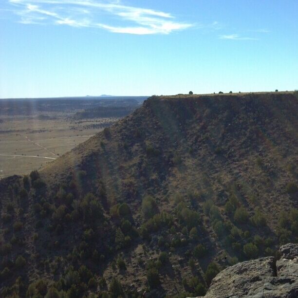 A rugged mountain landscape with sparse vegetation and a clear sky.