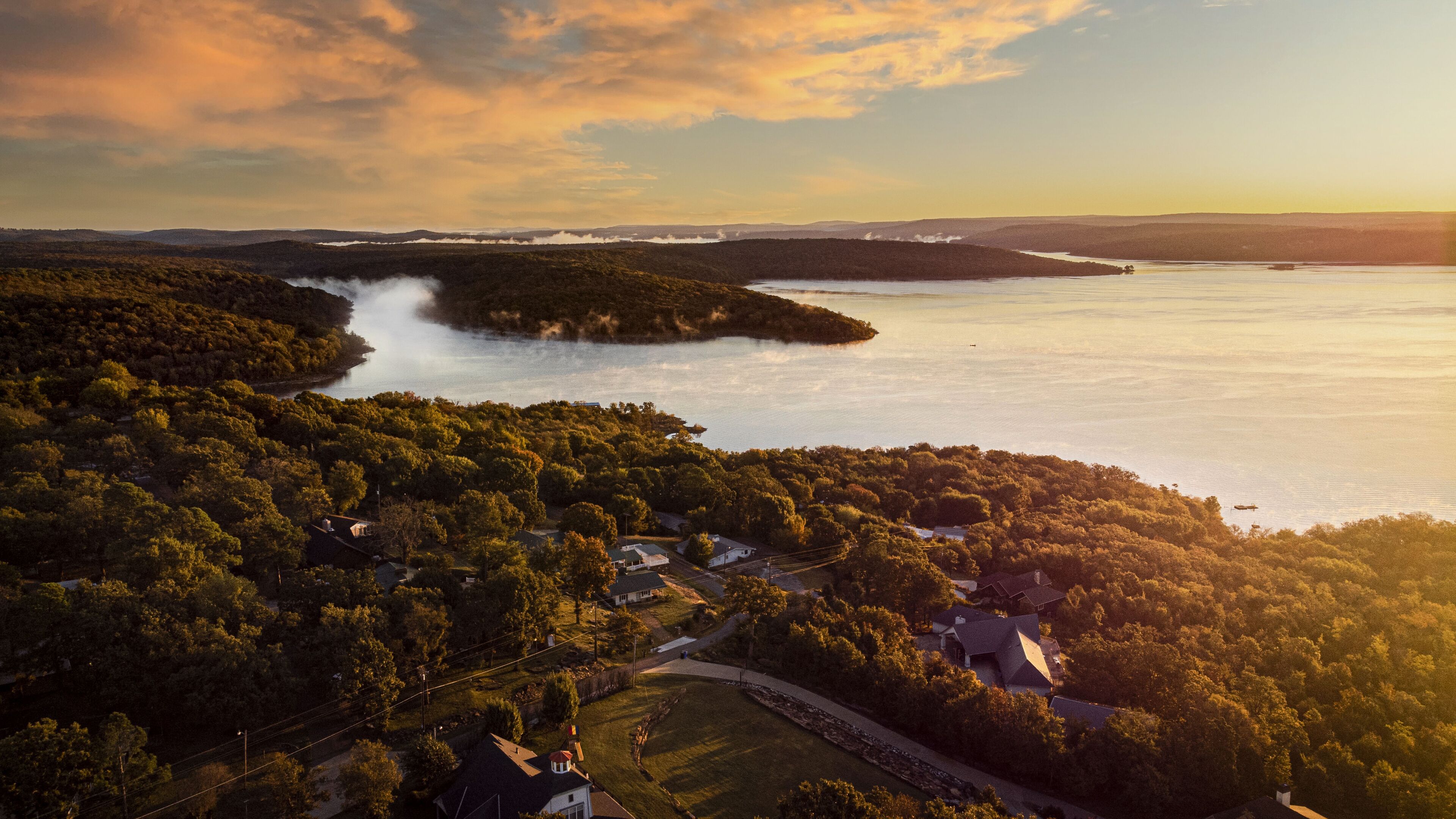 A coastal landscape with a forested area, a lake, and a small settlement with houses and roads.
