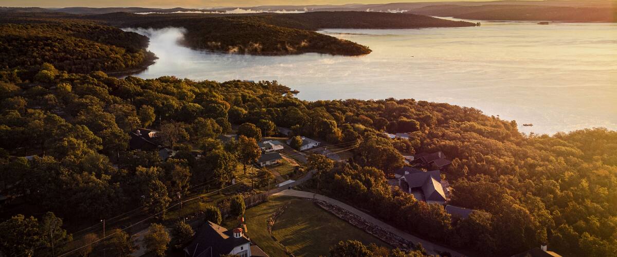 A coastal landscape with a forested area, a lake, and a small settlement with houses and roads.