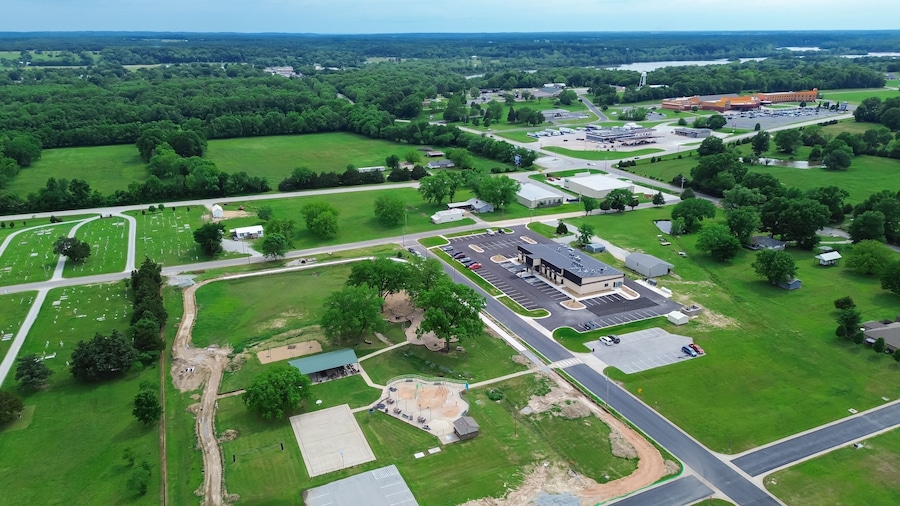 An aerial view of a campus with green fields, a parking lot, and several buildings.