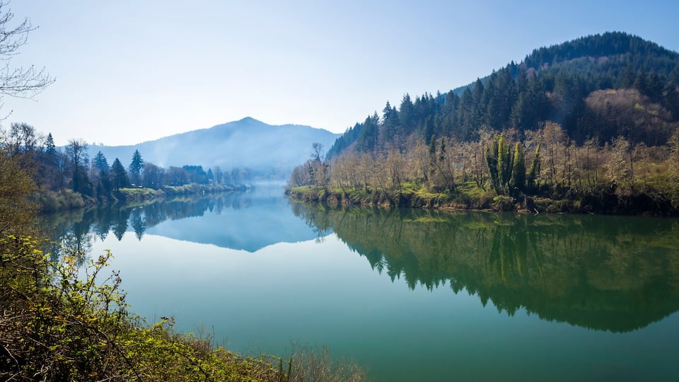 A calm lake surrounded by forested hills and mountains.