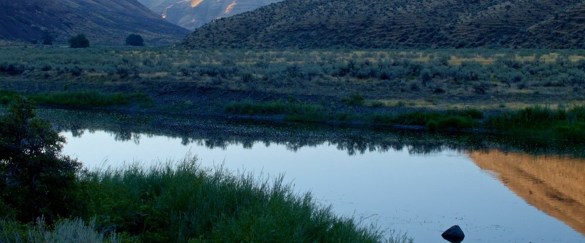 A calm river reflecting the surrounding hills.