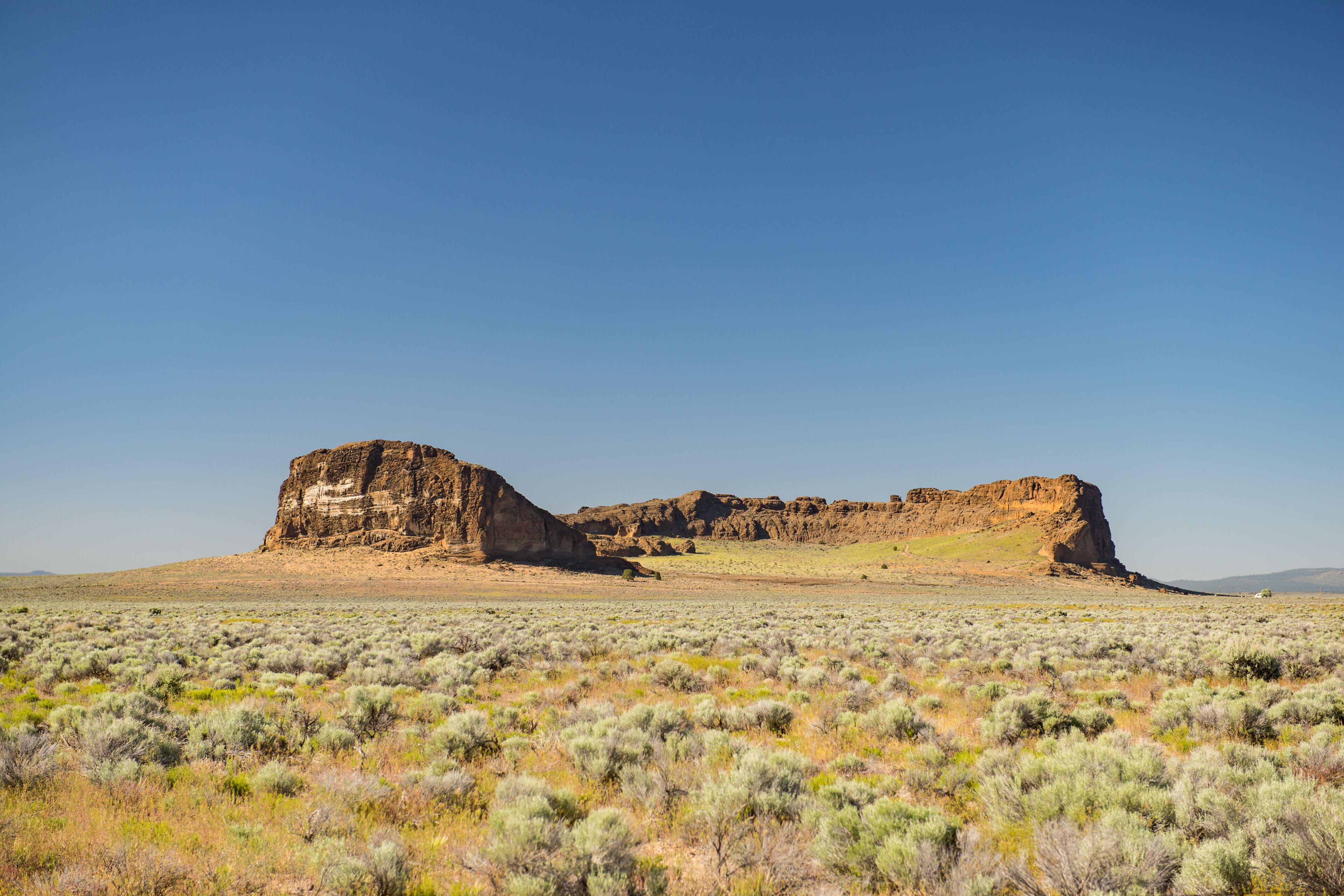 A desert landscape with sparse vegetation and prominent rock formations.