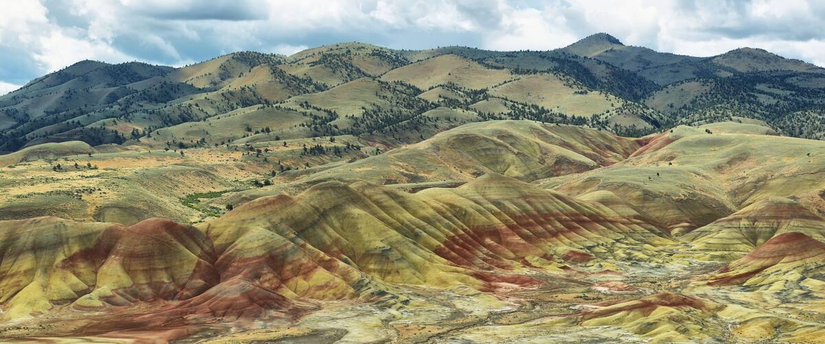 A landscape with rolling hills and a mountain range in the background.