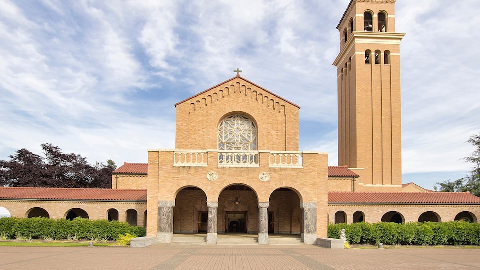 A large brick church with a tall bell tower and arched walkways.