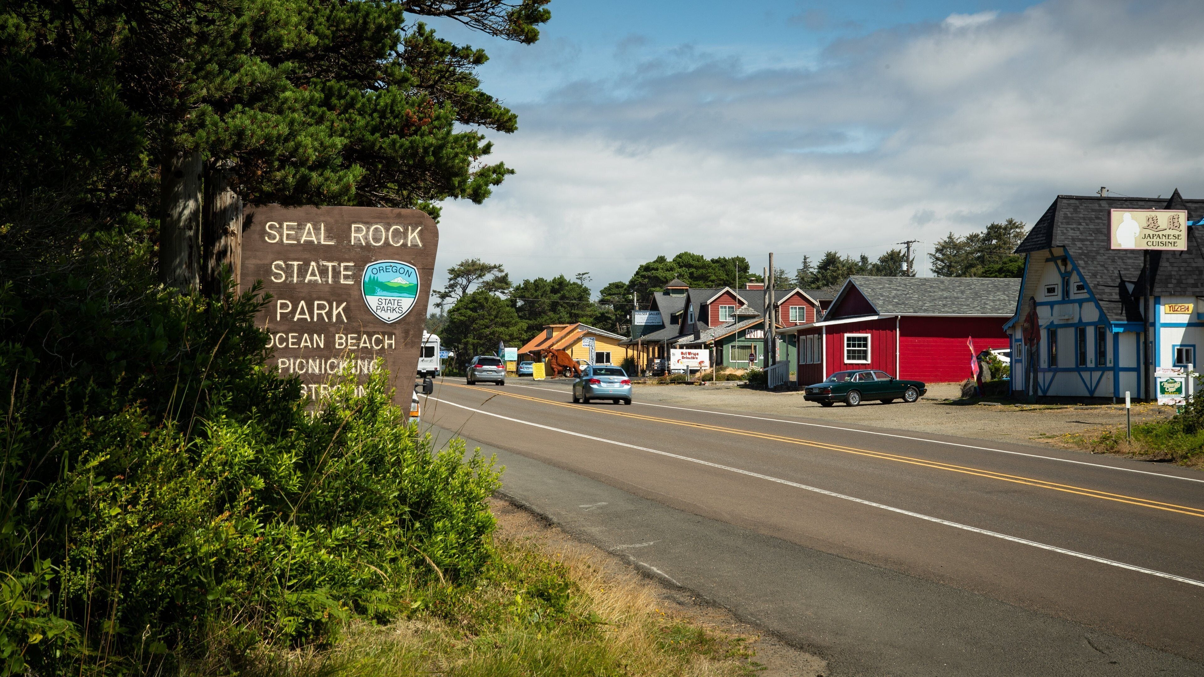 A road with a sign for Seal Rock State Park and a Japanese restaurant.