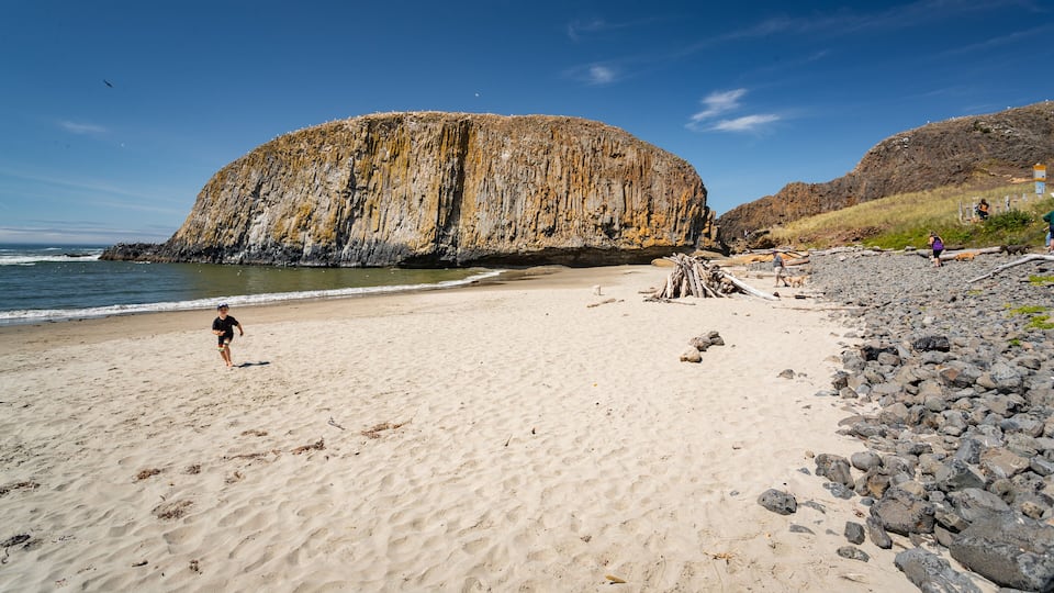 A sandy beach with a large rock formation in the background.