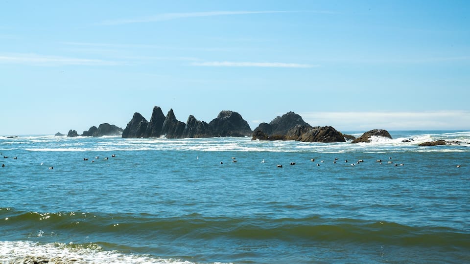A coastal landscape with rocky outcrops and a clear blue sky.