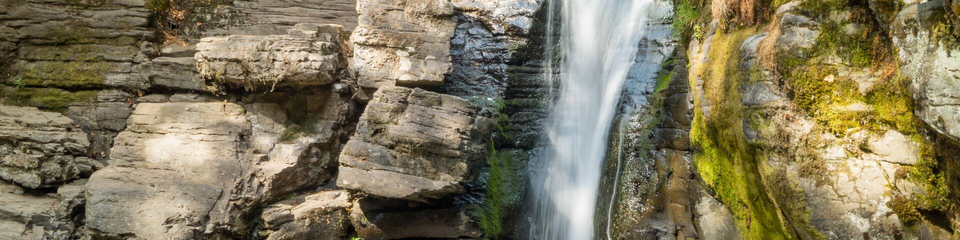 A waterfall cascading down a rocky cliff surrounded by moss-covered stones.