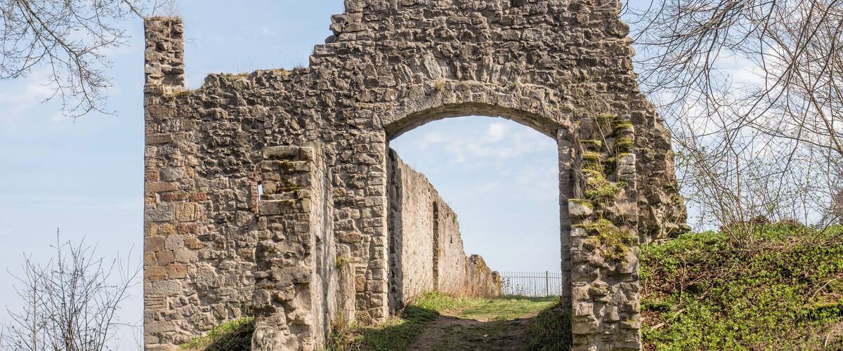 An ancient stone archway with a dirt path leading through it.