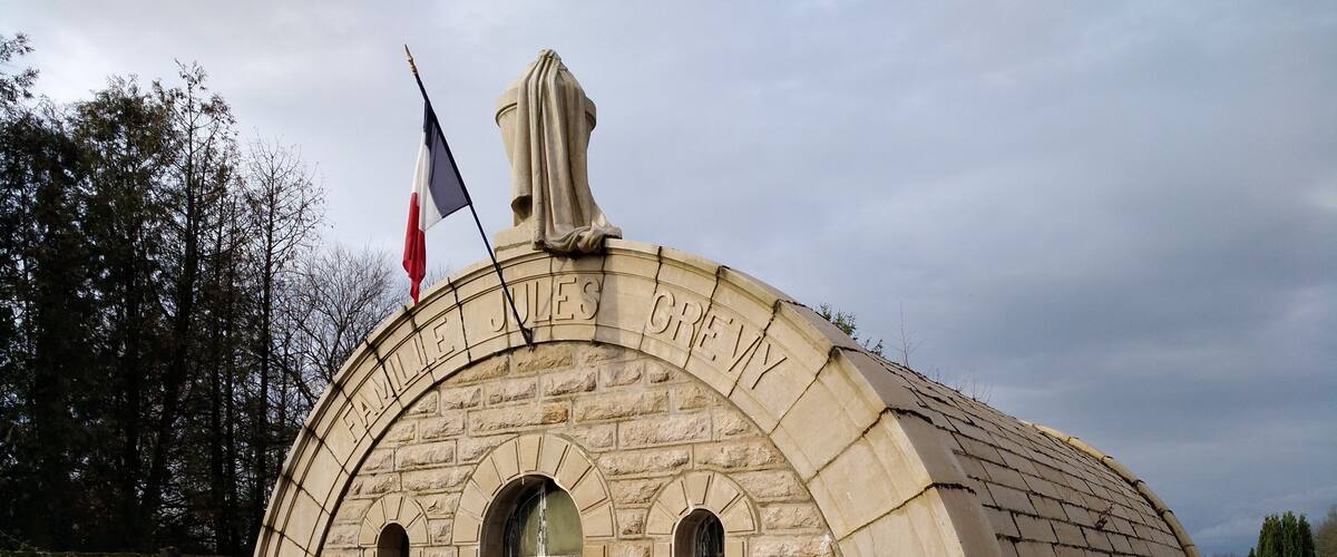 A stone building with an arched entrance and a flagpole.