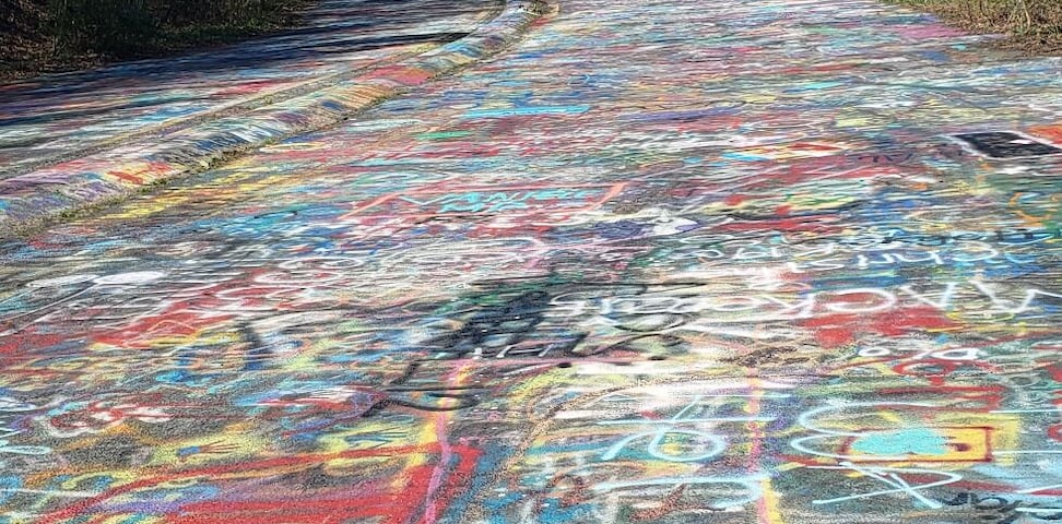 Uma estrada coberta por grafites coloridos.
