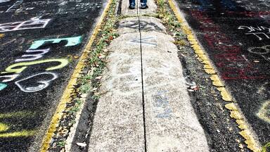 Uma pessoa em uma estrada com grafites e folhagem de outono.