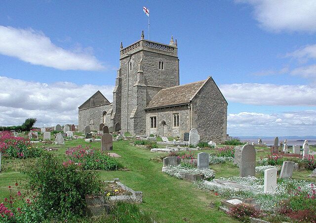 A church with a tower and a cemetery with headstones.
