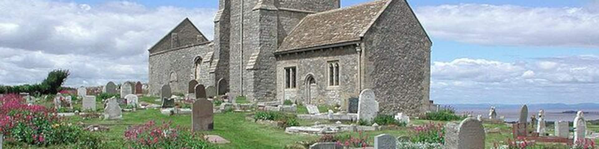 A church with a tower and a cemetery with headstones.