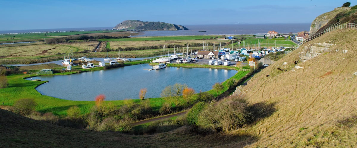 A coastal marina with boats, a small hill, and a distant island.