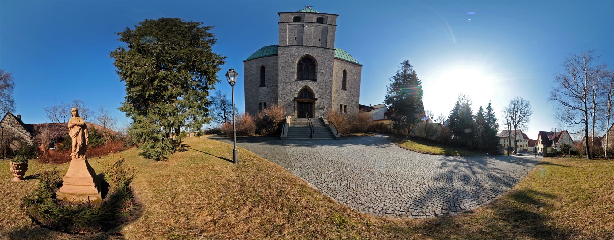 A church with a tower, a statue, and a cobblestone path.