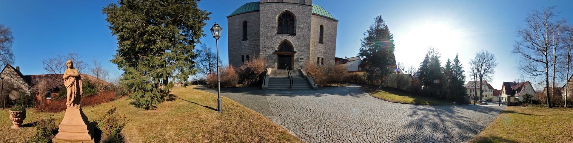 A church with a tower, a statue, and a cobblestone path.