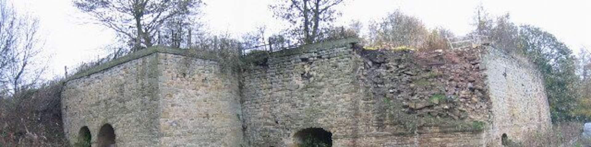 Fourstones Lime Kilns. These are the remains of a 19th century lime kiln. This large example contains at least four separate lime kilns. Limestone was built in kilns such as this to produce lime, which was used to make cement or improve soil quality. What a shame there is so much rubbish in front of this lime kiln. This is an important piece of industrial heritage and should be respected as much as more high profile ancient monuments.
