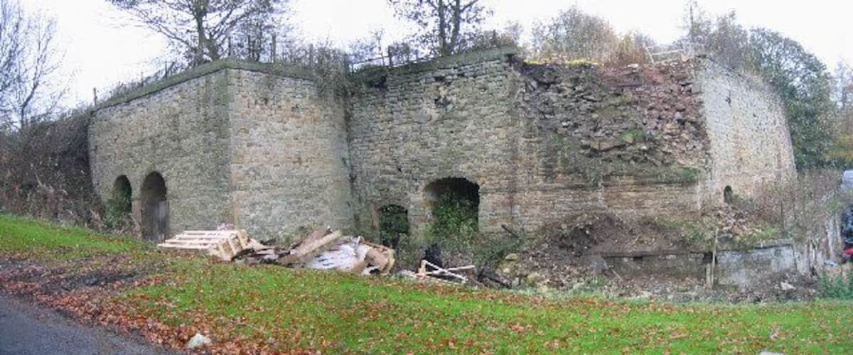 An old stone building with arched windows and a collapsed section.