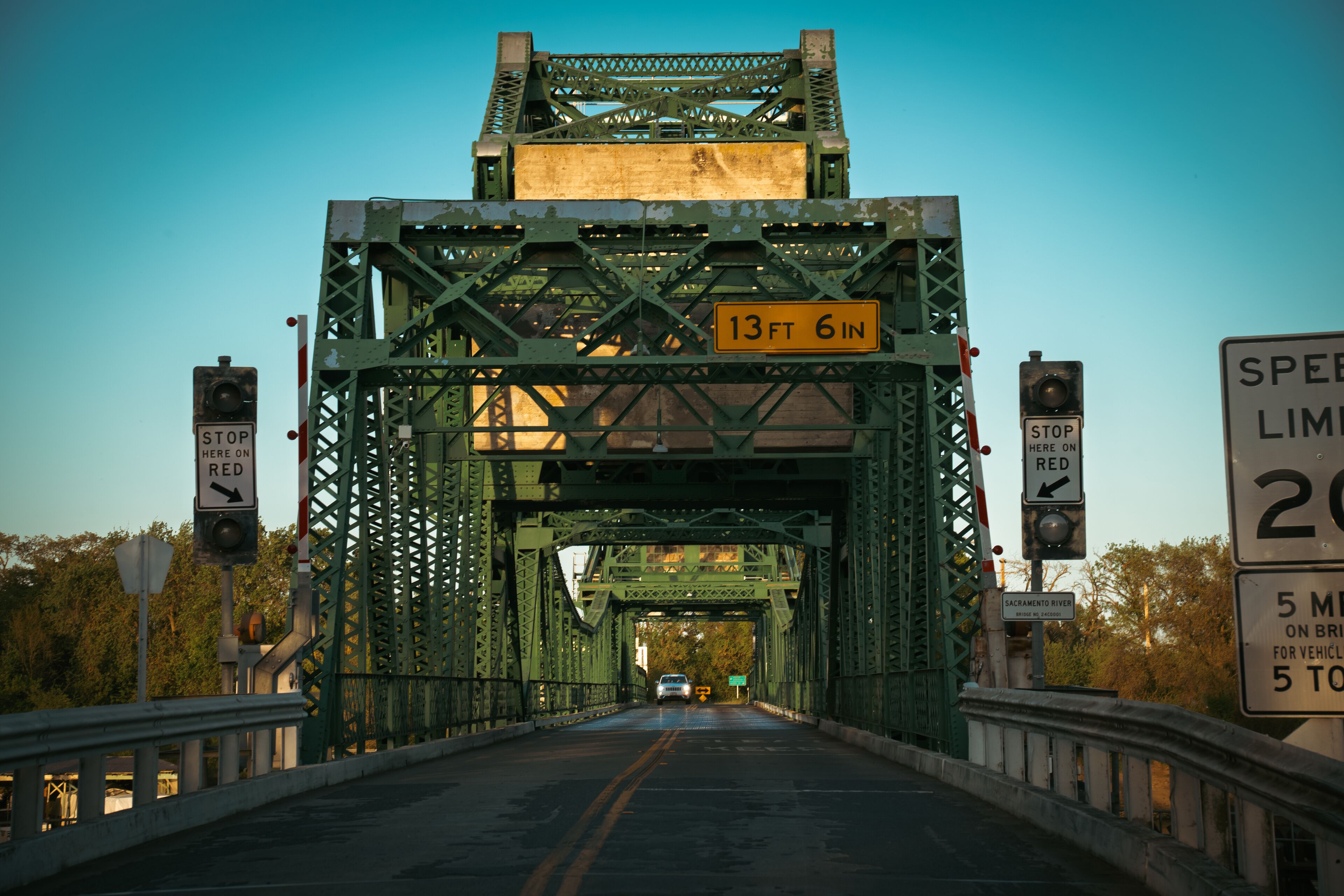 A green metal bridge with a height limit sign of 13 ft 6 in.