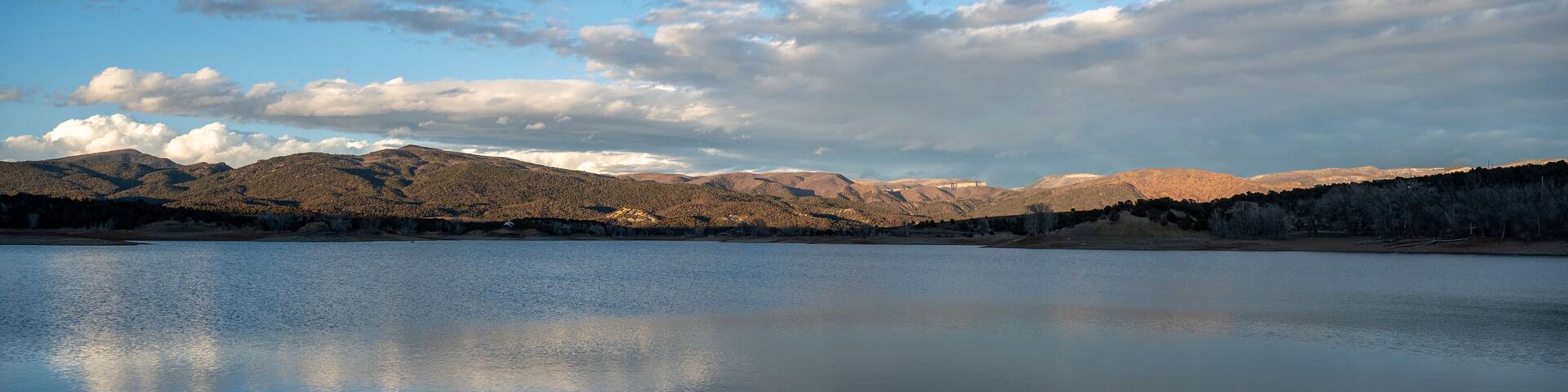 Colorful sunset cloudscape over Grass Valley Reservoir in Harvey Gap State Park, Colorado reflected in lake's calm water.