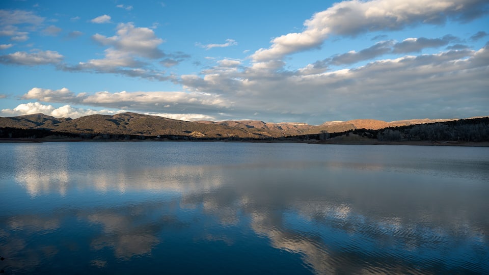 A calm lake reflecting the sky and mountains.