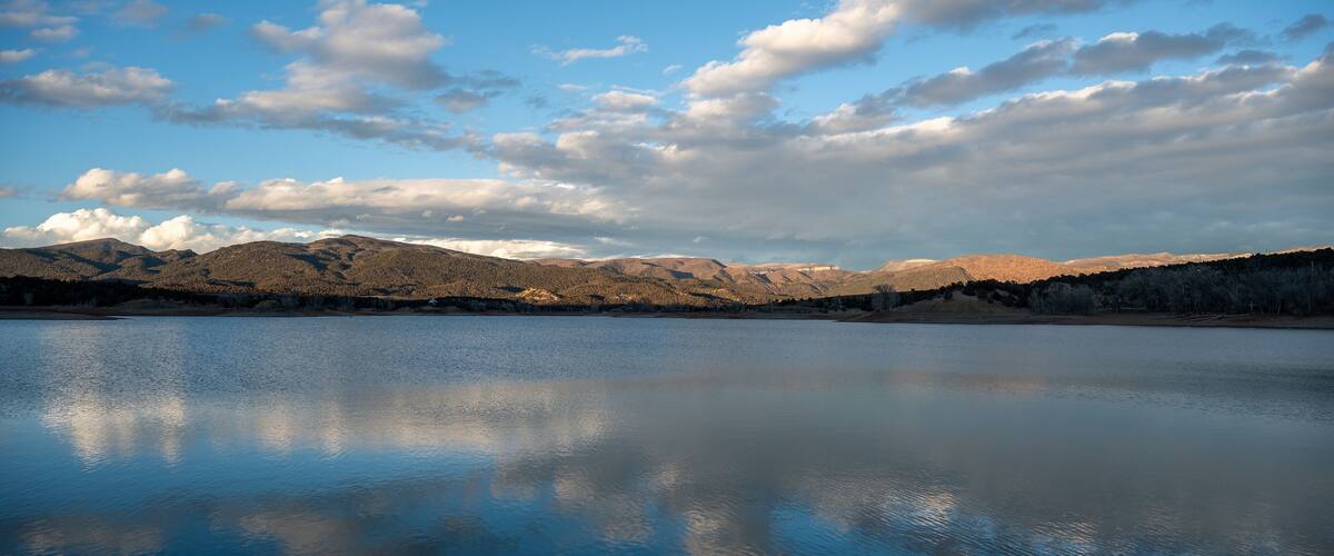 A calm lake reflecting the sky and mountains.