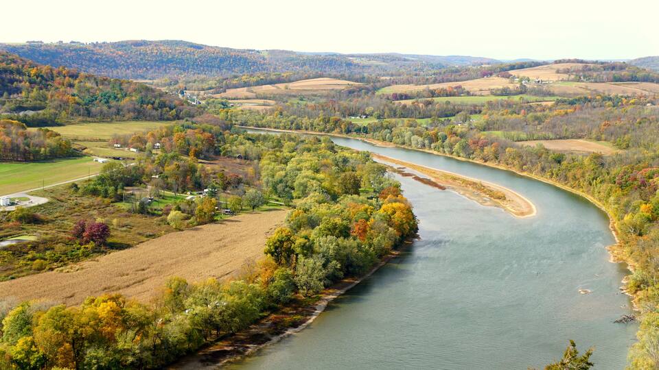 The aerial view of the Susquehanna River surrounded by striking color of fall foliage near Wyalusing, Pennsylvania, U.S