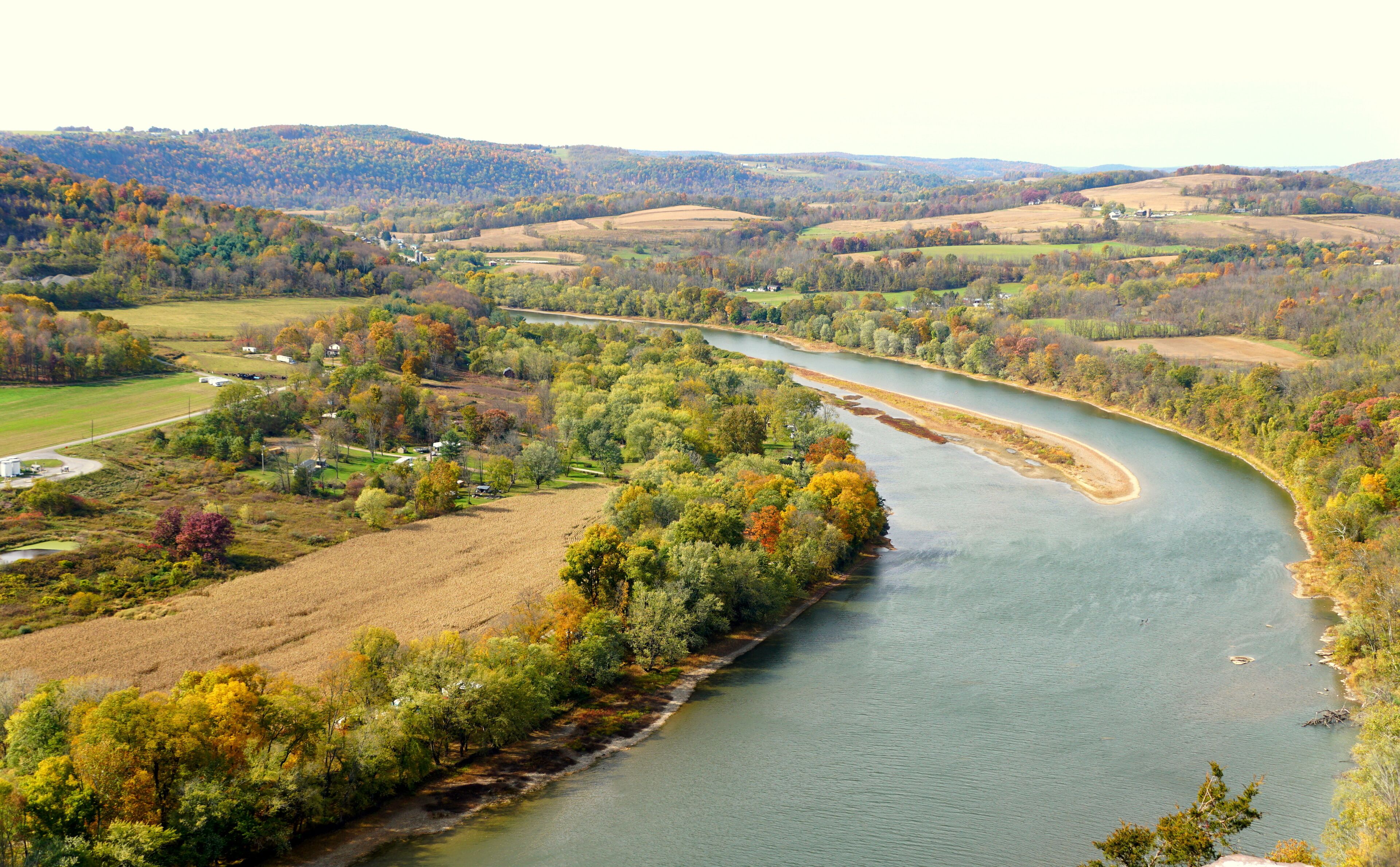 A river winding through a valley with autumn-colored trees and rolling hills in the background.
